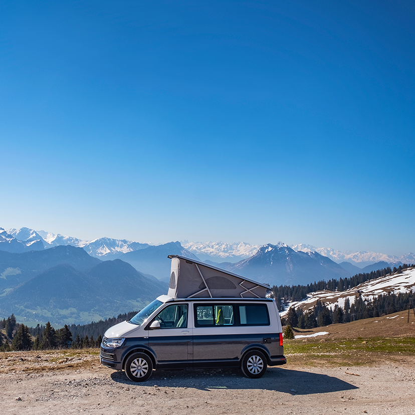 Campervan with pop-top up, looking over a snowy mountain view