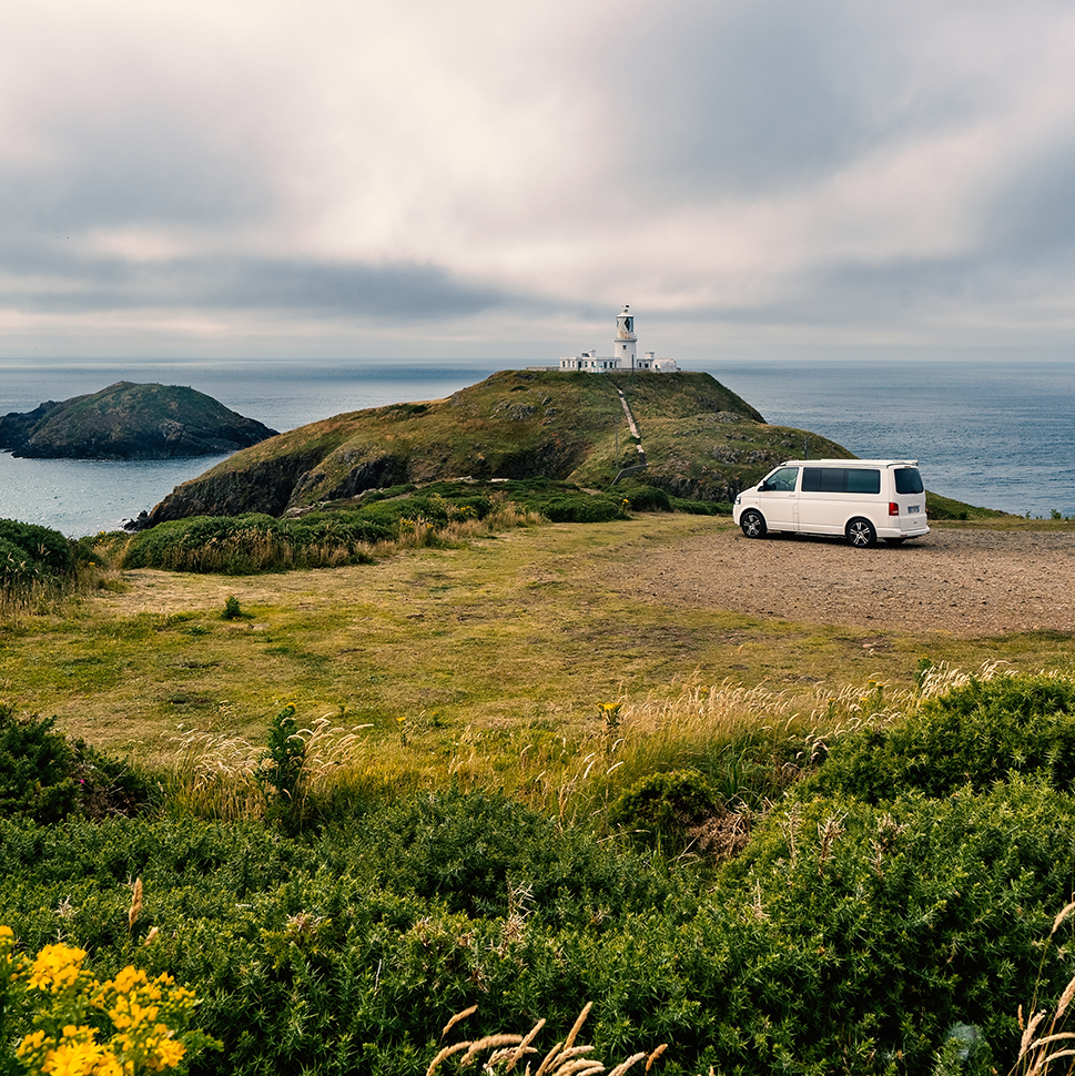 van overlooking lighthouse on a clifftop
